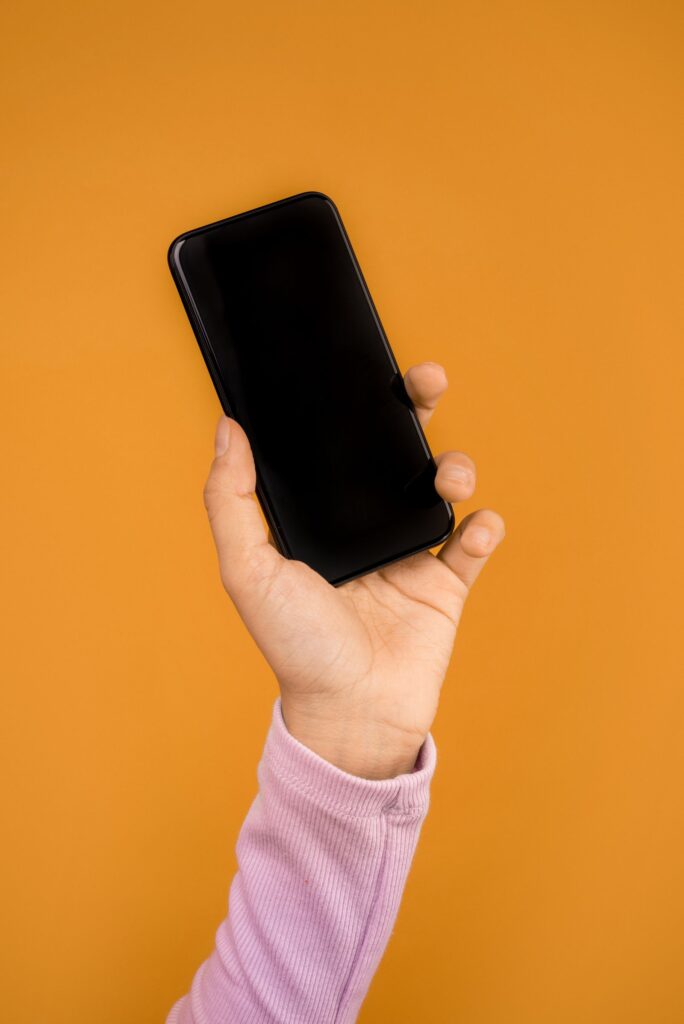 A hand holding a smartphone against a bright orange background
