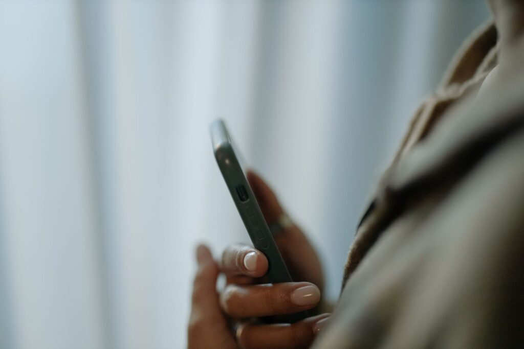 A person holding a smartphone near a bright window