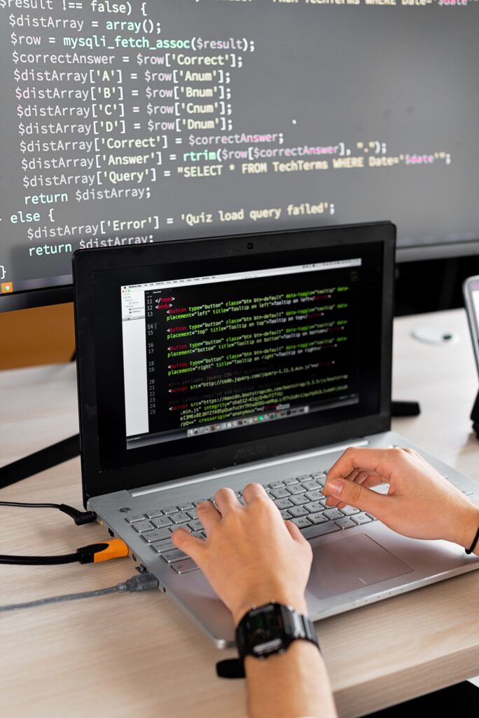 A laptop connected to an external monitor showing source code